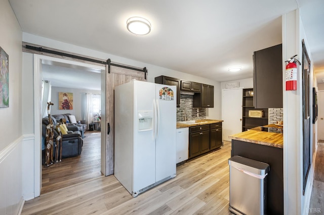 206 Huffmond St, Gretna, VA 24557 - kitchen with white appliances, dark brown cabinets, tasteful backsplash, a barn door, and light wood finished floors