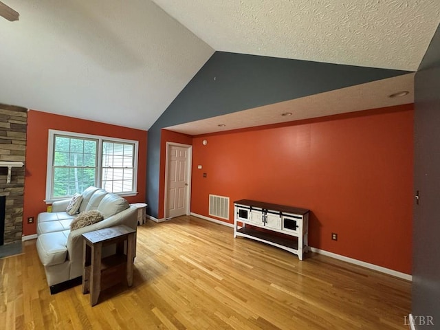 8 Northgate Ct, Lynch Station, VA 24571 - living room with a stone fireplace, lofted ceiling, light wood finished floors, and a textured ceiling