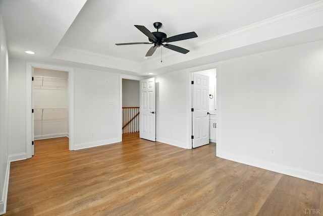 1036 Brownstone Dr, Forest, VA 24551 - unfurnished bedroom with light wood finished floors, recessed lighting, a tray ceiling, crown molding, and a walk in closet