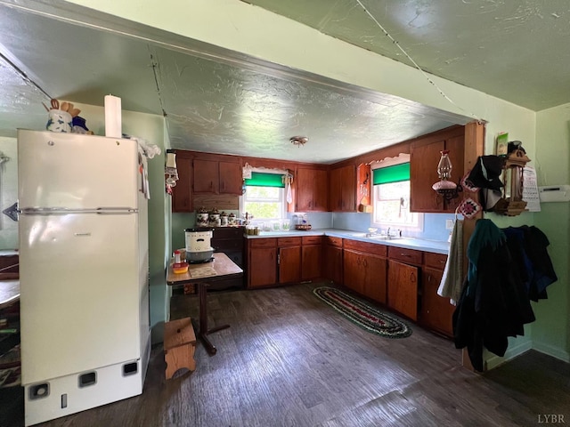 8288 Red House Rd, Phenix, VA 23959 - kitchen with freestanding refrigerator, dark wood-style floors, light countertops, and brown cabinets