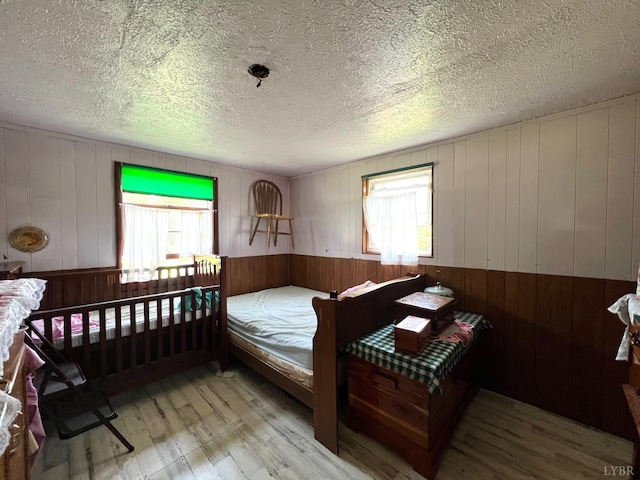 8288 Red House Rd, Phenix, VA 23959 - bedroom featuring wood-type flooring, wooden walls, a textured ceiling, and a wainscoted wall
