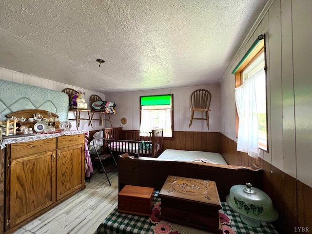 8288 Red House Rd, Phenix, VA 23959 - bedroom featuring wooden walls, light wood-style floors, a textured ceiling, and a wainscoted wall