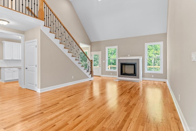 1290 Ivy Creek Dr, Forest, VA 24551 - unfurnished living room with high vaulted ceiling, light wood-style flooring, stairway, and a fireplace with flush hearth