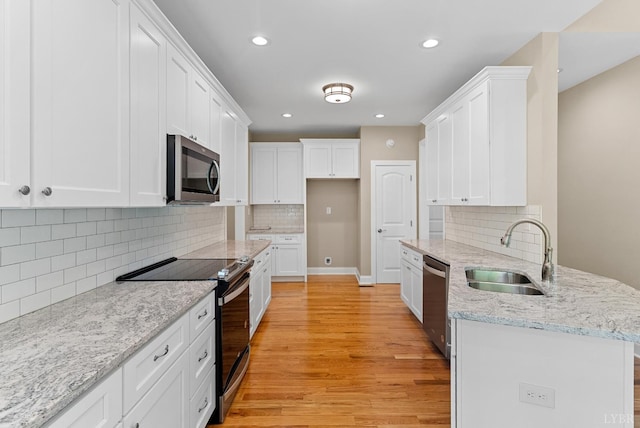 1290 Ivy Creek Dr, Forest, VA 24551 - kitchen with stainless steel appliances, a peninsula, light wood finished floors, white cabinetry, and decorative backsplash