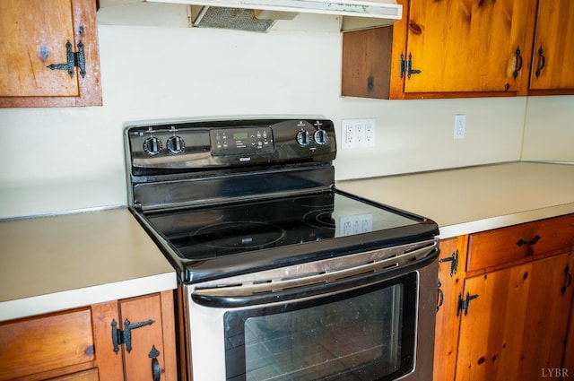4550 Pumping Station Rd, Appomattox, VA 24522 - kitchen with stainless steel electric stove, light countertops, brown cabinetry, and extractor fan