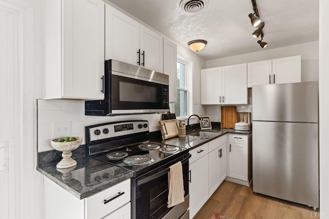 186 Dulwich Dr, Amherst, VA 24521 - kitchen featuring appliances with stainless steel finishes, white cabinetry, light wood finished floors, track lighting, and backsplash
