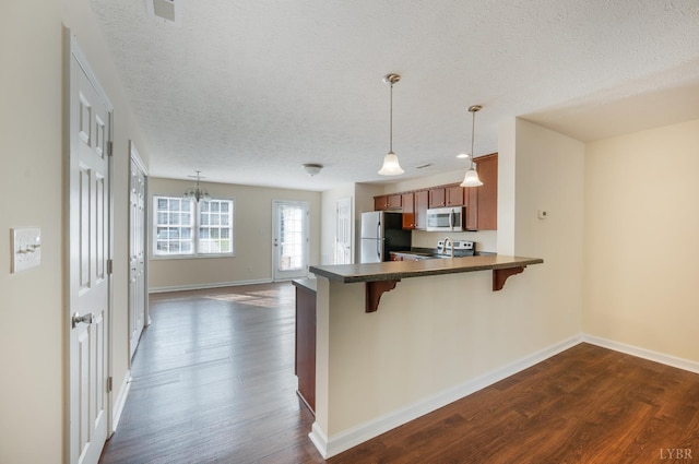 106 Colonnade St, Lynchburg, VA 24502 - kitchen featuring stainless steel appliances, brown cabinetry, dark wood-style flooring, dark countertops, and a peninsula