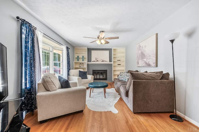 1246 Rainbow Forest Dr, Lynchburg, VA 24502 - living area with ceiling fan, a textured ceiling, wood finished floors, a glass covered fireplace, and built in features