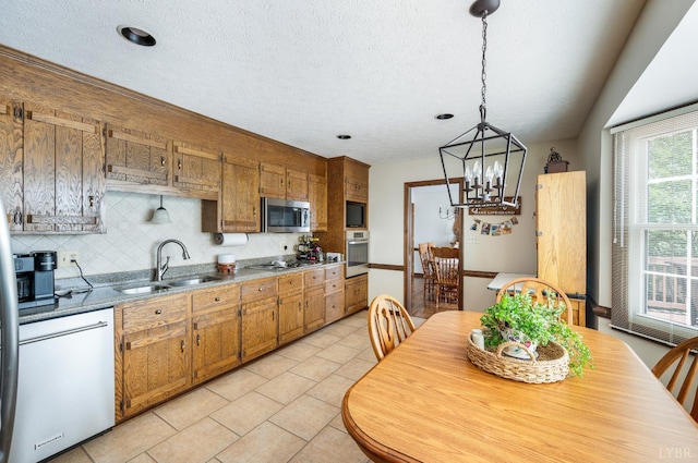 1159 Cifax Rd, Forest, VA 24551 - kitchen with stainless steel appliances, a chandelier, brown cabinetry, decorative backsplash, and light tile patterned floors