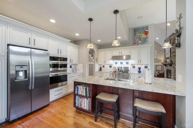 1424 Lake Manor Dr, Forest, VA 24551 - kitchen with stainless steel appliances, under cabinet range hood, decorative backsplash, white cabinetry, and a kitchen bar