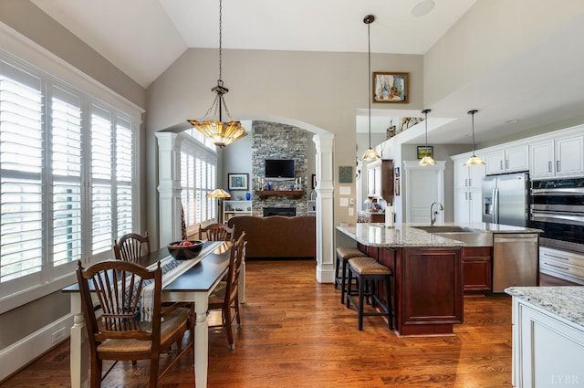 1424 Lake Manor Dr, Forest, VA 24551 - dining area with plenty of natural light, high vaulted ceiling, a fireplace, decorative columns, and dark wood-type flooring