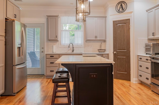 1507 Helmsdale Dr, Forest, VA 24551 - kitchen featuring appliances with stainless steel finishes, light wood finished floors, a breakfast bar, tasteful backsplash, and a center island
