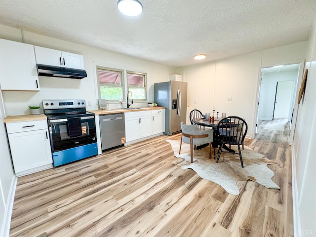 1033 8th St, Altavista, VA 24517 - kitchen with appliances with stainless steel finishes, under cabinet range hood, butcher block counters, light wood-style floors, and a textured ceiling