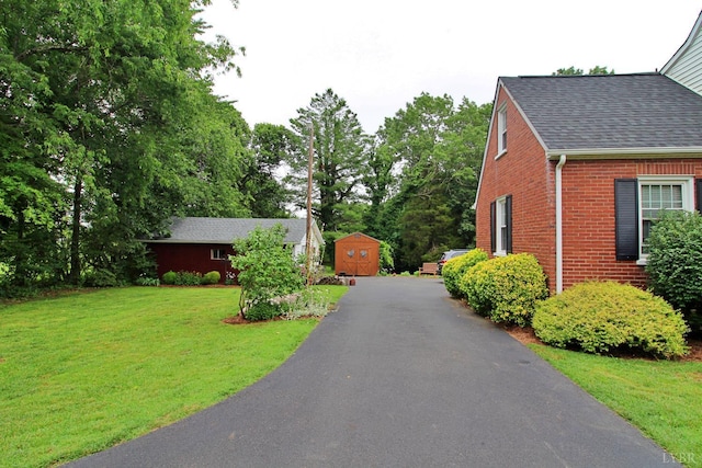 1538 Redfields Rd, Appomattox, VA 24522 - view of side of home with brick siding, a shingled roof, a yard, a storage unit, and view of scattered trees