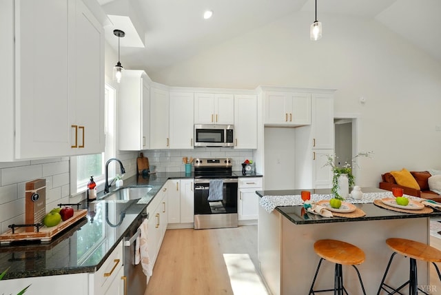 201 Thomas Rd, Lynchburg, VA 24501 - kitchen featuring appliances with stainless steel finishes, white cabinetry, high vaulted ceiling, light wood-style flooring, and a kitchen bar