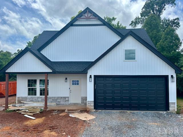 128 Riverside Dr, Lynchburg, VA 24503 - modern farmhouse featuring driveway, stone siding, roof with shingles, and an attached garage