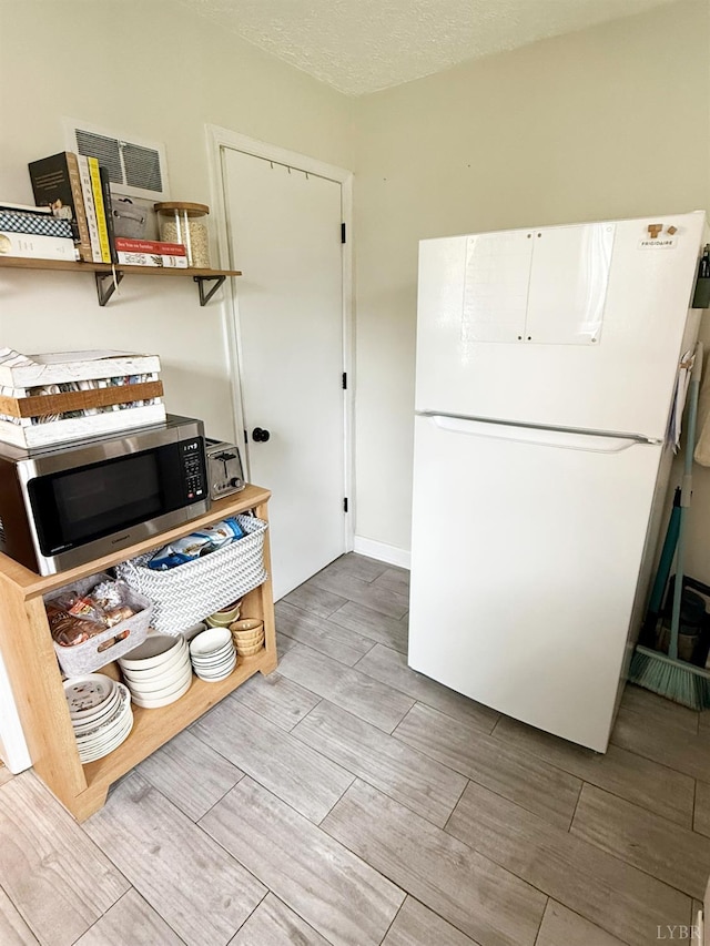1309 Cherokee Ave, Lynchburg, VA 24502 - kitchen with freestanding refrigerator, stainless steel microwave, wood finish floors, and white cabinetry
