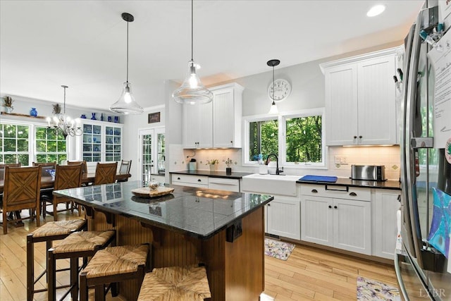 802 Lake Vista Dr, Forest, VA 24551 - kitchen with freestanding refrigerator, light wood-style floors, decorative backsplash, a center island, and white cabinets