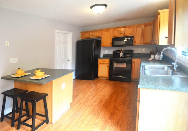3600 Old Forest Rd Unit 113, Lynchburg, VA 24502 - kitchen featuring black appliances, a peninsula, dark countertops, a kitchen breakfast bar, and light wood-style floors