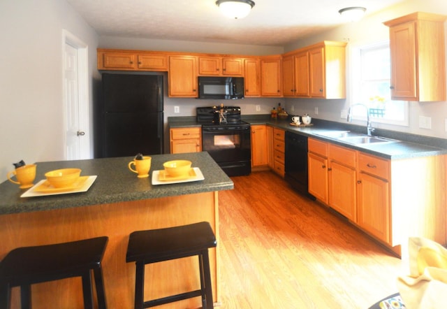 3600 Old Forest Rd Unit 113, Lynchburg, VA 24502 - kitchen with black appliances, a breakfast bar, light wood finished floors, and dark countertops