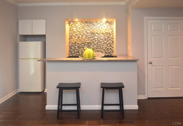 3600 Old Forest Rd Unit 113, Lynchburg, VA 24502 - kitchen with freestanding refrigerator, a breakfast bar area, backsplash, white cabinetry, and crown molding