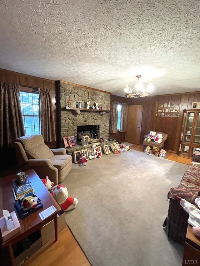 1102 Smith St, Bedford, VA 24523 - living room featuring healthy amount of natural light, a textured ceiling, a chandelier, wood walls, and a stone fireplace