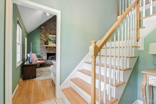 702 Kings Rd, Lynchburg, VA 24502 - stairs featuring vaulted ceiling, a stone fireplace, wood finished floors, and a textured ceiling