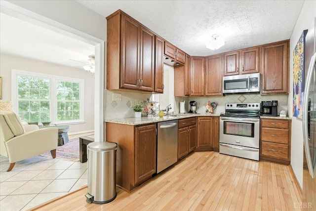 702 Kings Rd, Lynchburg, VA 24502 - kitchen featuring appliances with stainless steel finishes, light wood-style floors, backsplash, ceiling fan, and a textured ceiling
