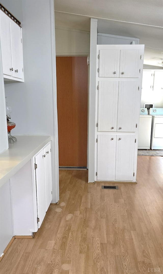 271 Candlemakers Ln, Rustburg, VA 24588 - kitchen featuring light wood-style flooring, washing machine and clothes dryer, white cabinetry, and light countertops