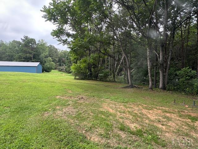 2022 New Chapel Rd, Rustburg, VA 24588 - view of grassy yard with a wooded view, an outbuilding, and an outdoor structure