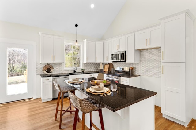 7 Hickory Cove Ln, Moneta, VA 24121 - kitchen featuring appliances with stainless steel finishes, white cabinetry, a kitchen breakfast bar, lofted ceiling, and backsplash