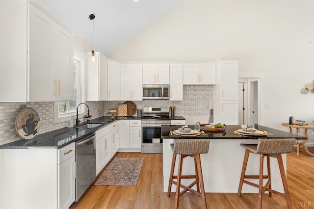 7 Hickory Cove Ln, Moneta, VA 24121 - kitchen with appliances with stainless steel finishes, white cabinetry, a breakfast bar, light wood-style floors, and high vaulted ceiling