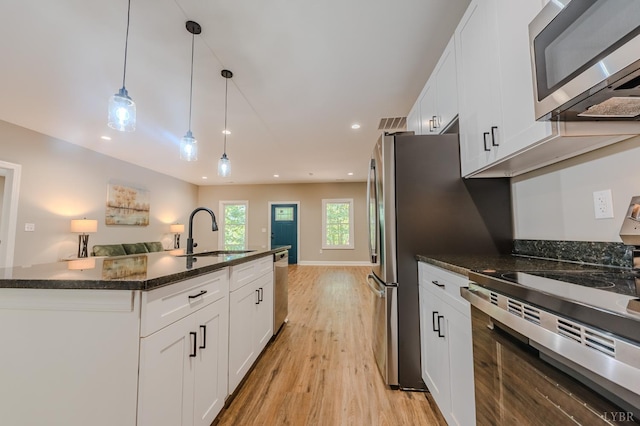 109 Tosh Ln, Goodview, VA 24095 - kitchen with stainless steel appliances, open floor plan, light wood-style flooring, white cabinets, and decorative light fixtures