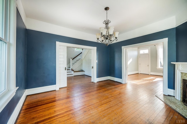 838 Rivermont Ave, Lynchburg, VA 24504 - unfurnished dining area featuring a chandelier, stairs, hardwood / wood-style flooring, and a high end fireplace
