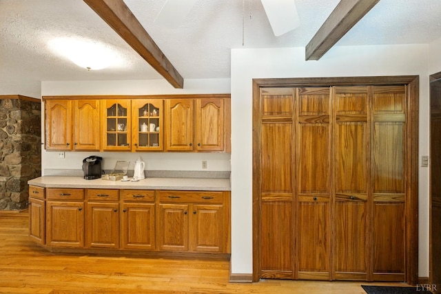 239 Briarcliff Ln, Madison Heights, VA 24572 - kitchen featuring beam ceiling, glass insert cabinets, brown cabinets, light wood finished floors, and light countertops