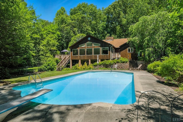 239 Briarcliff Ln, Madison Heights, VA 24572 - swimming pool with stairway, a deck, a diving board, and a view of trees
