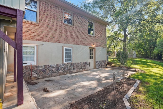 2294 High Peak Rd, Monroe, VA 24574 - view of side of home with a patio area, stone siding, a yard, stucco siding, and brick siding