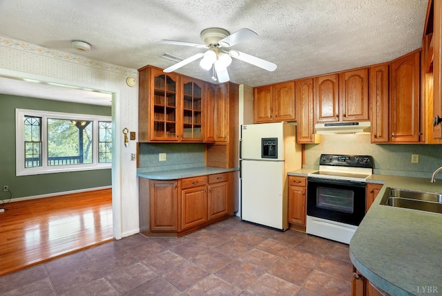 2294 High Peak Rd, Monroe, VA 24574 - kitchen with range with electric stovetop, white fridge with ice dispenser, under cabinet range hood, brown cabinets, and glass insert cabinets