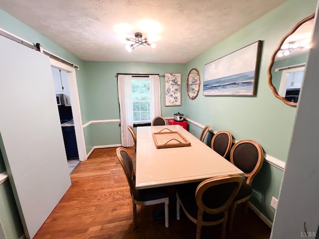 68 Cardwell Ln, Lynchburg, VA 24504 - dining space with light wood-style flooring, a textured ceiling, and a barn door