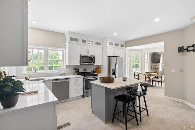 1505 Chestnut Grove Rd, Appomattox, VA 24522 - kitchen with appliances with stainless steel finishes, decorative backsplash, a breakfast bar area, light countertops, and white cabinets