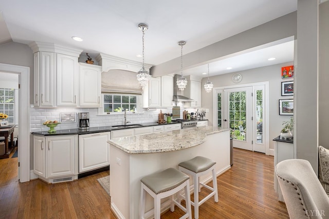 1517 Linden Ave, Lynchburg, VA 24503 - kitchen featuring wood finished floors, a kitchen island, white cabinets, decorative backsplash, and a breakfast bar