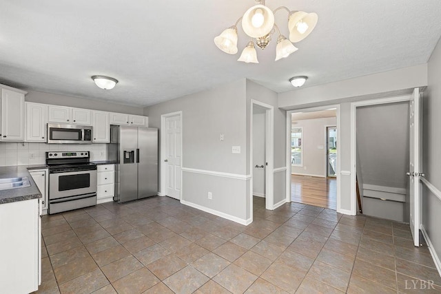 1036 Middle View Dr, Forest, VA 24551 - kitchen with stainless steel appliances, dark countertops, a chandelier, white cabinets, and tasteful backsplash