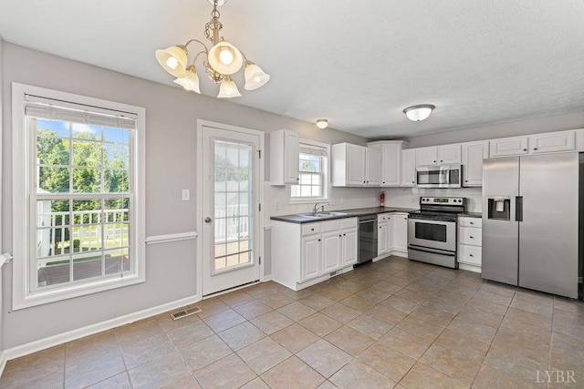1036 Middle View Dr, Forest, VA 24551 - kitchen with appliances with stainless steel finishes, a chandelier, dark countertops, white cabinets, and pendant lighting