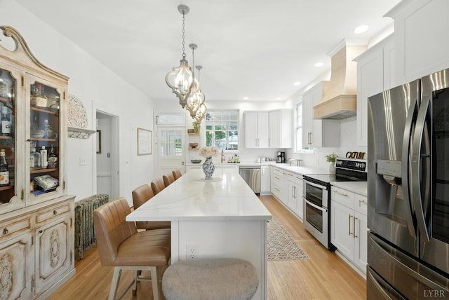 2212 Rivermont Ave, Lynchburg, VA 24503 - kitchen with appliances with stainless steel finishes, premium range hood, a kitchen bar, radiator heating unit, and light wood-type flooring