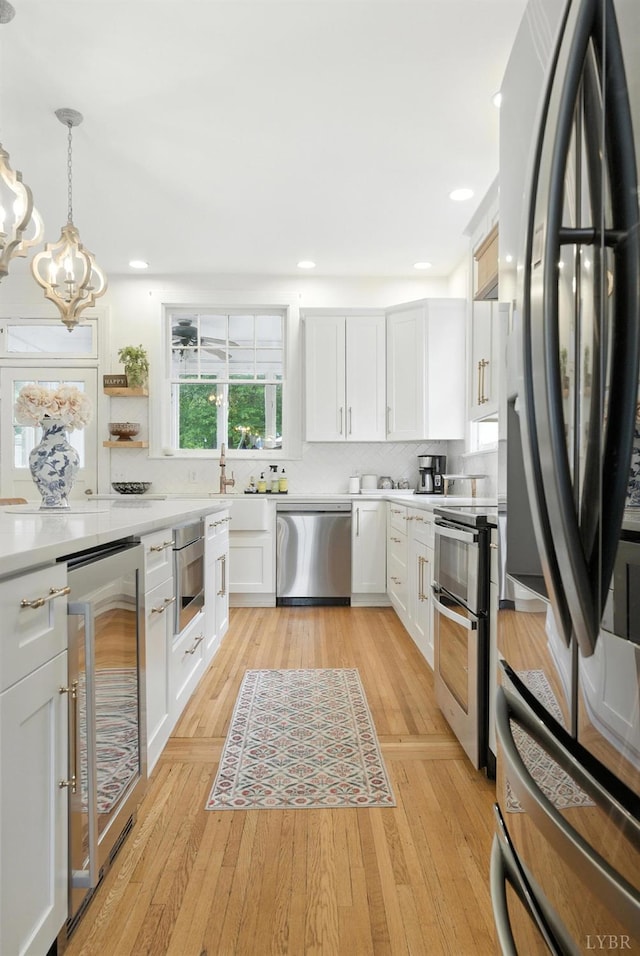 2212 Rivermont Ave, Lynchburg, VA 24503 - kitchen with appliances with stainless steel finishes, wine cooler, light countertops, a chandelier, and white cabinetry