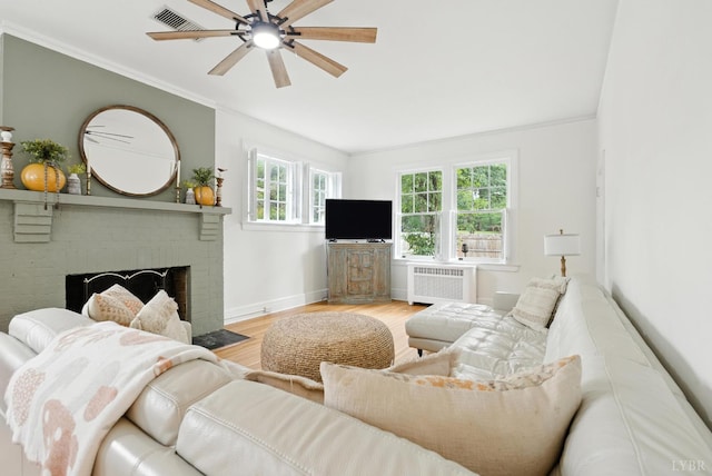 2212 Rivermont Ave, Lynchburg, VA 24503 - living room with radiator, wood finished floors, a brick fireplace, a ceiling fan, and ornamental molding