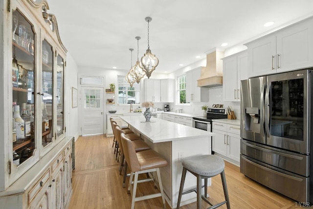 2212 Rivermont Ave, Lynchburg, VA 24503 - kitchen with appliances with stainless steel finishes, premium range hood, a breakfast bar area, light countertops, and a center island