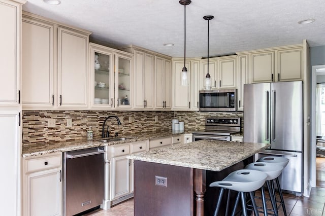102 Stirling Ct, Forest, VA 24551 - kitchen featuring appliances with stainless steel finishes, cream cabinetry, a center island, decorative backsplash, and decorative light fixtures