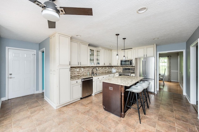 102 Stirling Ct, Forest, VA 24551 - kitchen with appliances with stainless steel finishes, a breakfast bar area, a kitchen island, backsplash, and light stone countertops