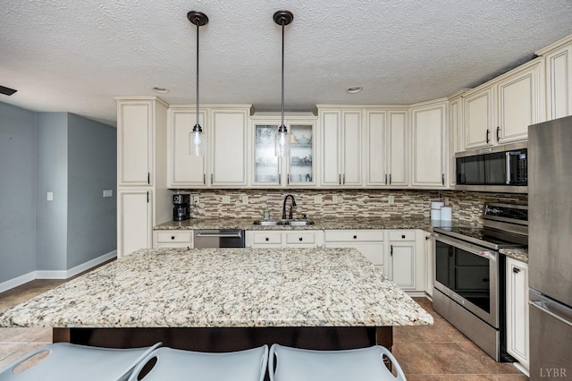 102 Stirling Ct, Forest, VA 24551 - kitchen featuring stainless steel appliances, cream cabinetry, a kitchen bar, backsplash, and pendant lighting